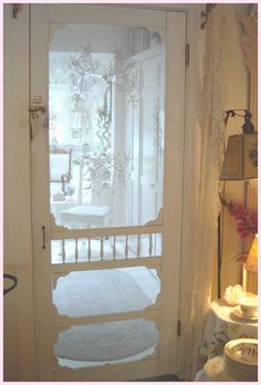 an open door with frosting on it in front of a table and lamp next to a window