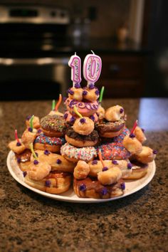 a birthday cake made out of doughnuts with candles on top is sitting on a plate