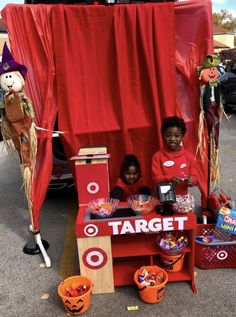 two children are standing in front of a target booth with halloween decorations on the table