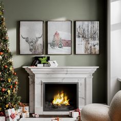 a living room with a christmas tree, fireplace and pictures on the wall above it