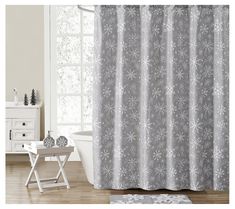 a shower curtain with snowflakes on it next to a bathtub and window