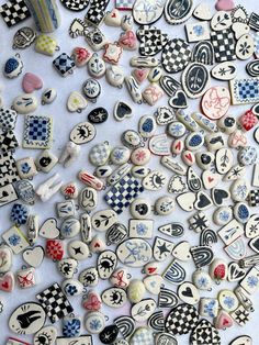 many different colored and shaped buttons on a white tablecloth with black and white checkered background