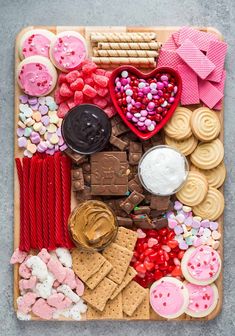 a wooden tray filled with lots of different types of cookies and candies on top of each other