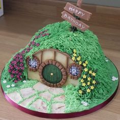 a birthday cake that looks like a hobbot house with flowers and grass on it