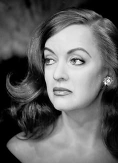 a black and white photo of a woman with long hair wearing an earring in her left hand