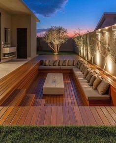 an outdoor living area with couches and lights on the side of the house at night