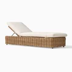 a wicker chaise lounger with white cushions