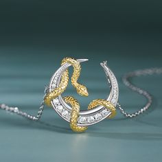 A majestic golden snake gracefully entwined around a shimmering silver crescent moon. It symbolizes the eternal dance of night and day, light and shadow. It's a poetic expression of elegance and mystery. It's perfect for those who seek to adorn themselves with timeless beauty and symbolism.Carat Weight: 0.348 ctStone Size: 1,1.2,1.7,2,0.8 mmStone Type: Jeulia® StoneNumber of Stones: 13 Stone Color: Diamond WhiteStone Shape: RoundWeight: 4.5 gWidth: 20.5 mmHeight: 21 mmThickness: 5 mmMaterial: 92 Luxury Sterling Silver Snake-shaped Jewelry, Elegant Silver Necklace With Sun And Moon Design, Golden Snake, Art Jewelry Design, Jewelry Drawing, Snake Pendant, Night And Day, Teaching Yoga, Diamond Jewelry Designs