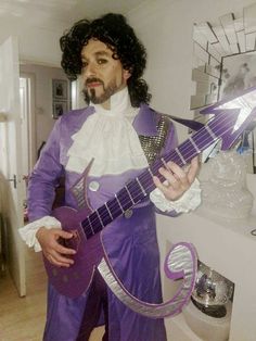 a man in a purple outfit is holding a guitar