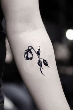 a black and white photo of a rose tattoo on the arm