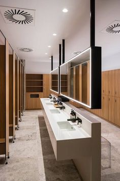 a row of sinks in a public restroom with mirrors and lights on the wall above them