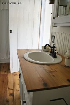 a bathroom with a sink, mirror and wooden counter top next to a white door