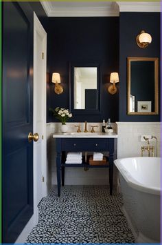 a bathroom with blue walls, white and gold fixtures and a black and white tile floor