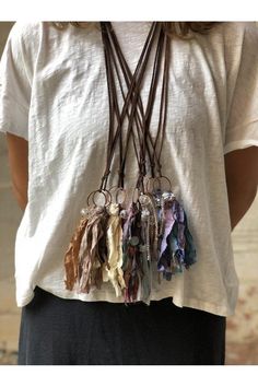 a woman wearing a white t - shirt and brown leather necklace with multicolored tassels