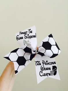 a person holding up a black and white soccer bow with the words forget the glass slippers on it