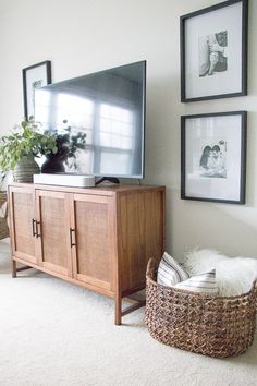 a flat screen tv sitting on top of a wooden cabinet next to a wicker basket