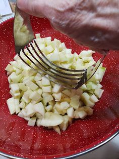 a person is cutting up some food on a red plate with a fork and knife