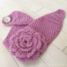 a crocheted pink hat with a flower on the front and a button in the middle