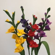 a vase filled with colorful flowers sitting on top of a wooden table next to a white wall