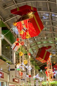 christmas decorations hanging from the ceiling in a shopping mall, with presents on display below