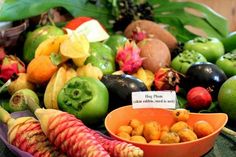 a bowl filled with lots of different types of fruit next to other fruits and vegetables