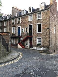 a cobblestone street with stone buildings on both sides and stairs leading up to the second story