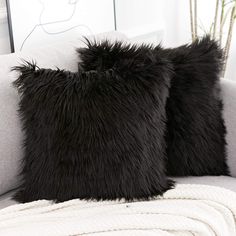 two black furry pillows sitting on top of a couch