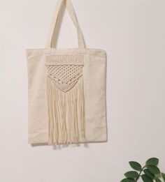 a tote bag hanging on a wall next to a plant