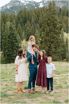 a family posing for a photo in front of some pine trees with mountains in the background