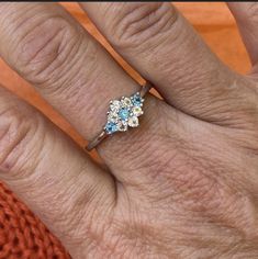 a woman's hand with an engagement ring on top of her finger and two blue stones in the middle