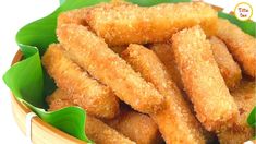 some fried food in a wooden bowl with green leaves on the side and white background