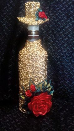 a bottle with a rose on it and a glitter topper in the shape of a hat