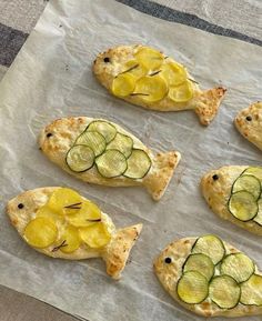 four fish shaped pizzas with cucumbers and slices of pickles on them