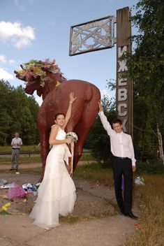 a bride and groom standing next to a giant elephant statue