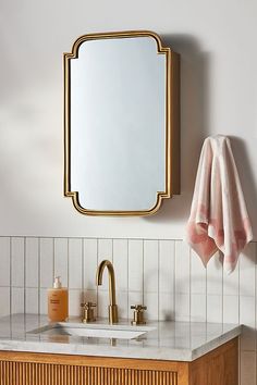 a bathroom with a sink, mirror and towel hanging on the wall next to it