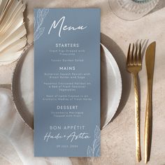 a menu card sitting on top of a white plate next to gold utensils