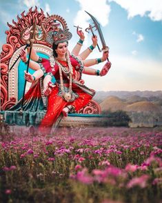 a woman sitting on top of a giant statue in the middle of a flower field