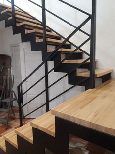 there is a wooden table and stairs in the room that has been painted white with black railings