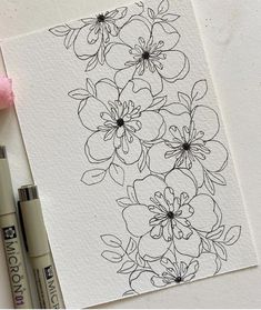 an ink pen and some flowers on top of a piece of paper next to two markers