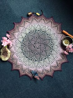 a crocheted doily is laying on the floor next to flowers and other items