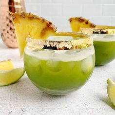 three glasses filled with green liquid and topped with sliced pineapples on the side