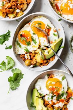 three bowls filled with eggs and vegetables on top of a white countertop next to other dishes