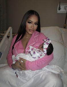 a woman holding a baby in her arms while sitting on top of a hospital bed