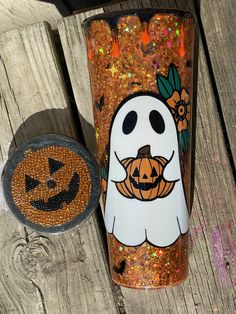 a halloween themed tumbler next to a jack - o'- lantern decoration on a wooden table