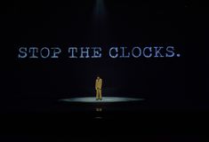 a man standing on top of a stage with the words stop the clocks