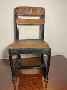 an old wooden chair sitting on top of a hard wood floor next to a white wall