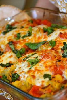 a close up of a pizza on a pan with cheese and spinach toppings