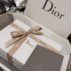 an open dior gift box with a ribbon on the side and a card in it