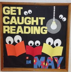 a sign that says get caught reading in may with cartoon eyes and bookmarks on it