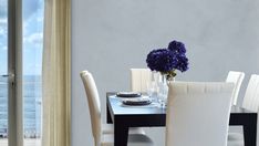 a dining room table with white chairs and blue flowers in vases on the table